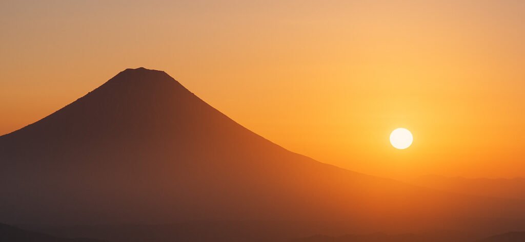 Sun rising behind a mountain, symbolizing self-discovery, clarity, and the journey toward lasting happiness