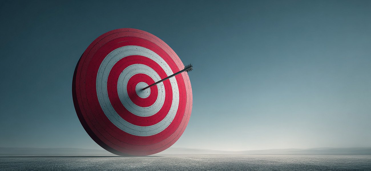 Symbol of focused action: a single arrow hits the bullseye on a large target in a wide open landscape